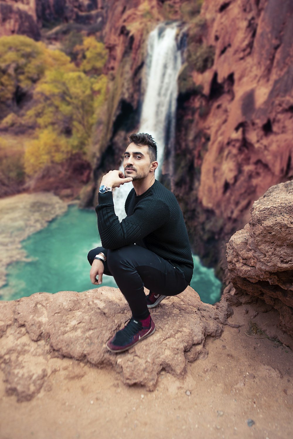 man sitting in front of waterfalls