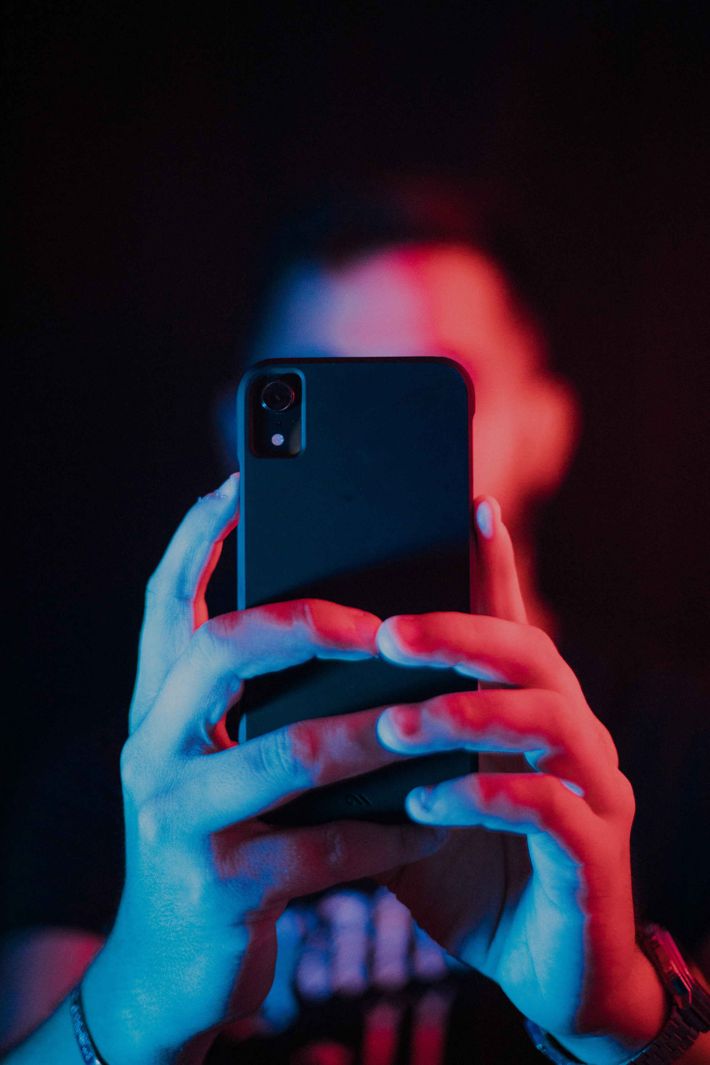 A person in a dark room holding a phone up close to their face