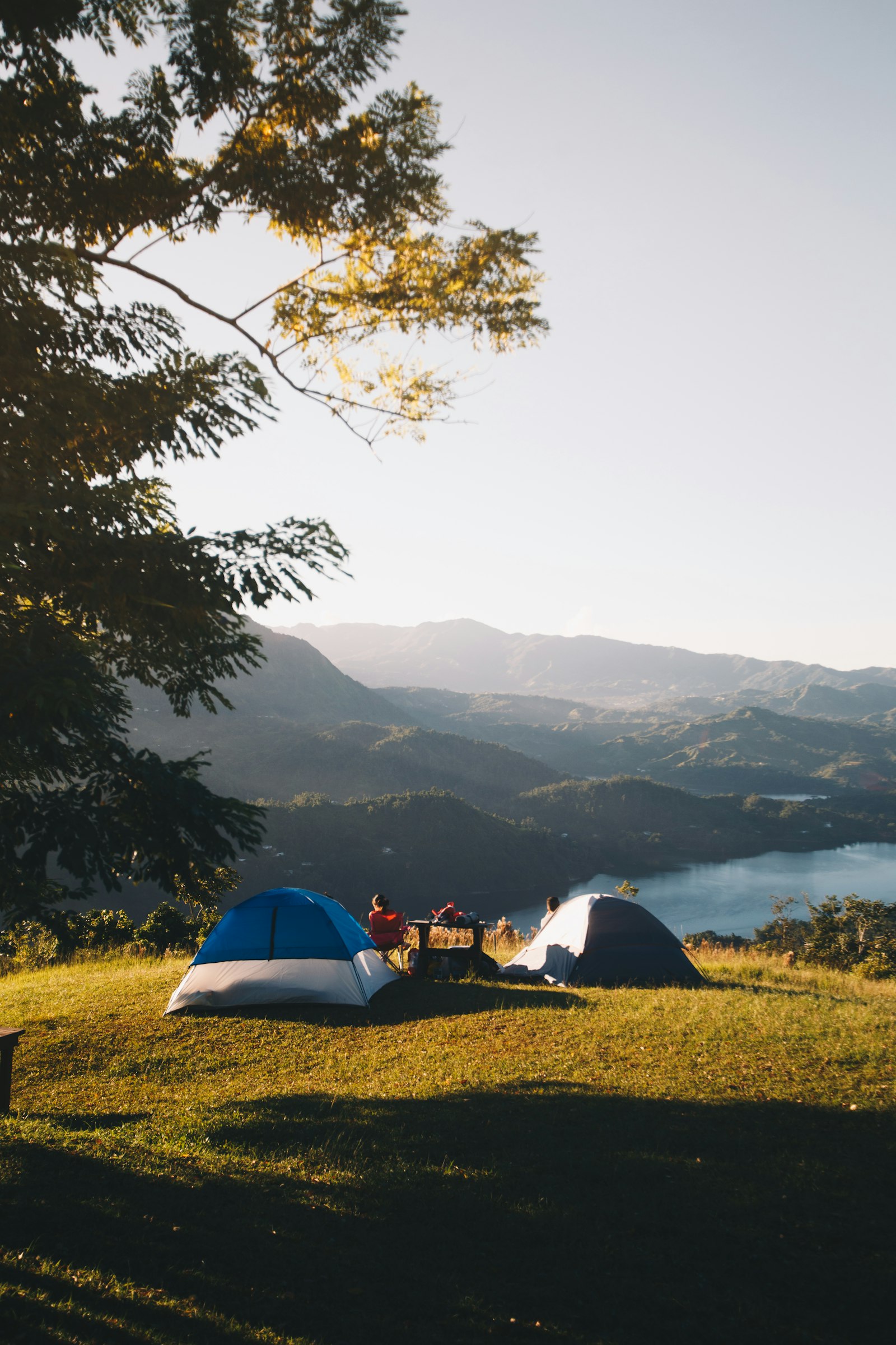 Deux tentes sur une prairie face à un lac de montagne