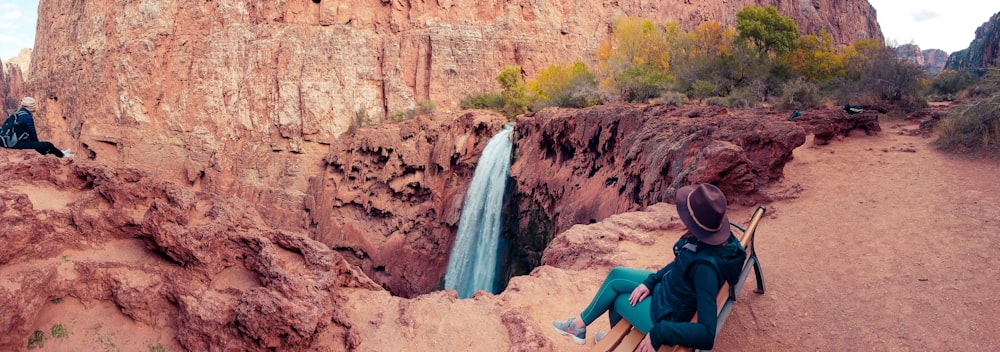 fotografia panoramica di persona seduta di fronte alle cascate