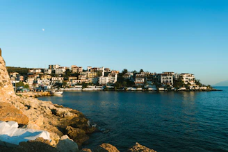 Portrait of Mauro Leitão standing by the coastline in Ericeira, with elegant seaside homes in the background.