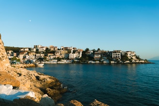 A warm, inviting Cypriot coastal town with charming houses and clear blue sea under a sunny sky.