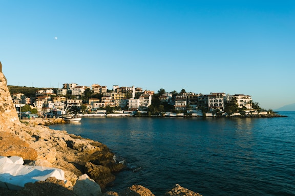 A warm, inviting Cypriot coastal town with charming houses and clear blue sea under a sunny sky.