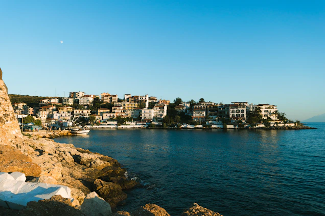 Portrait of Mauro Leitão standing by the coastline in Ericeira, with elegant seaside homes in the background.