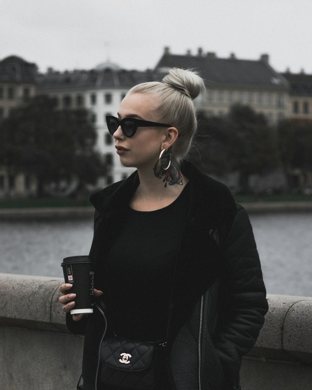 woman standing near body of water holding disposable cup