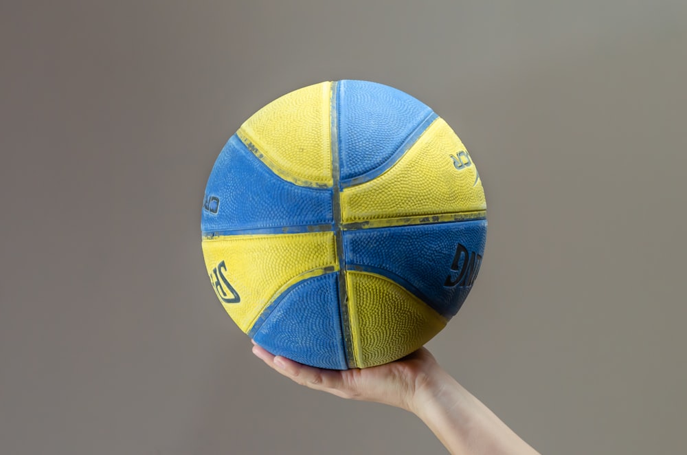 person holding blue and yellow Spalding basketball