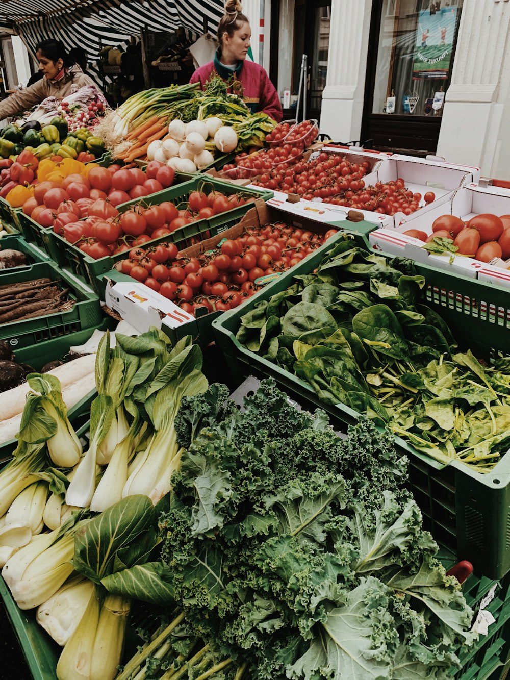 different vegetables on display and women standing near vegetable