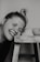 grayscale photo of woman smiling and leaning towards stool