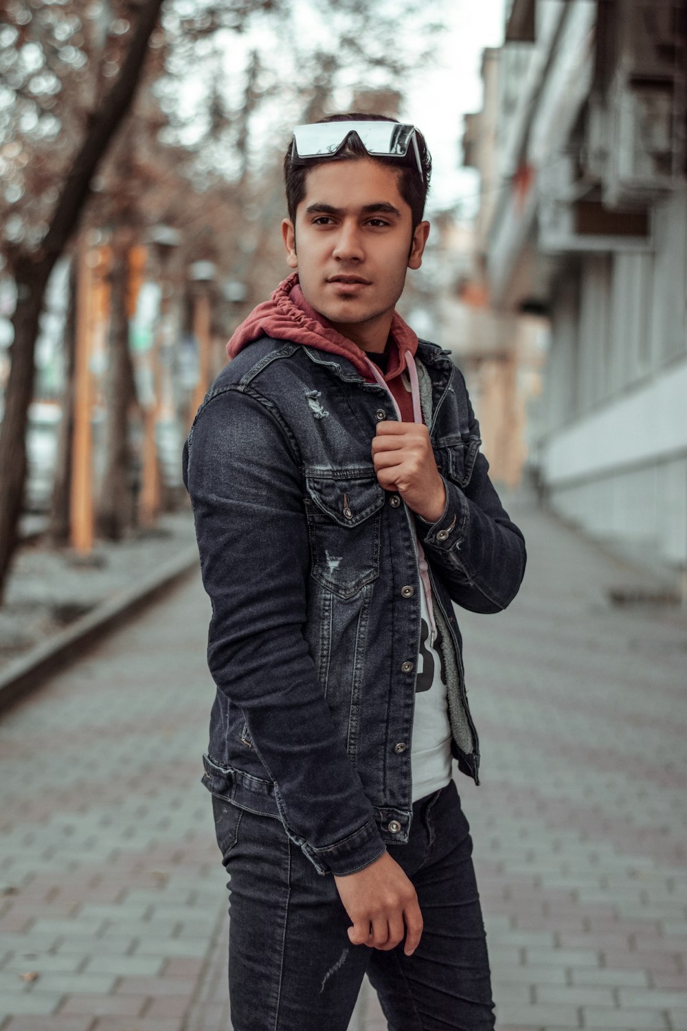 man in black denim jacket on bricked pavement