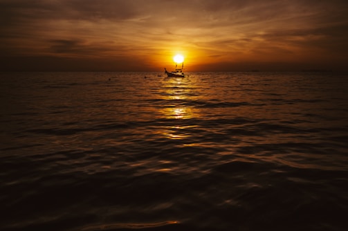 Sunset view from a boat with warm golden light reflecting on gentle waves.