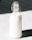 A glass bottle filled with milk is standing against a contrasting background. The bottle has a metal clasp and a rubber stopper at the top.