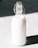 A glass bottle filled with milk is standing against a contrasting background. The bottle has a metal clasp and a rubber stopper at the top.