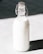 A glass bottle filled with milk is standing against a contrasting background. The bottle has a metal clasp and a rubber stopper at the top.