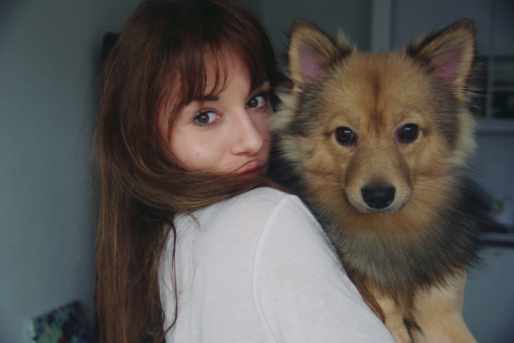 woman carrying a long-coated fawn dog