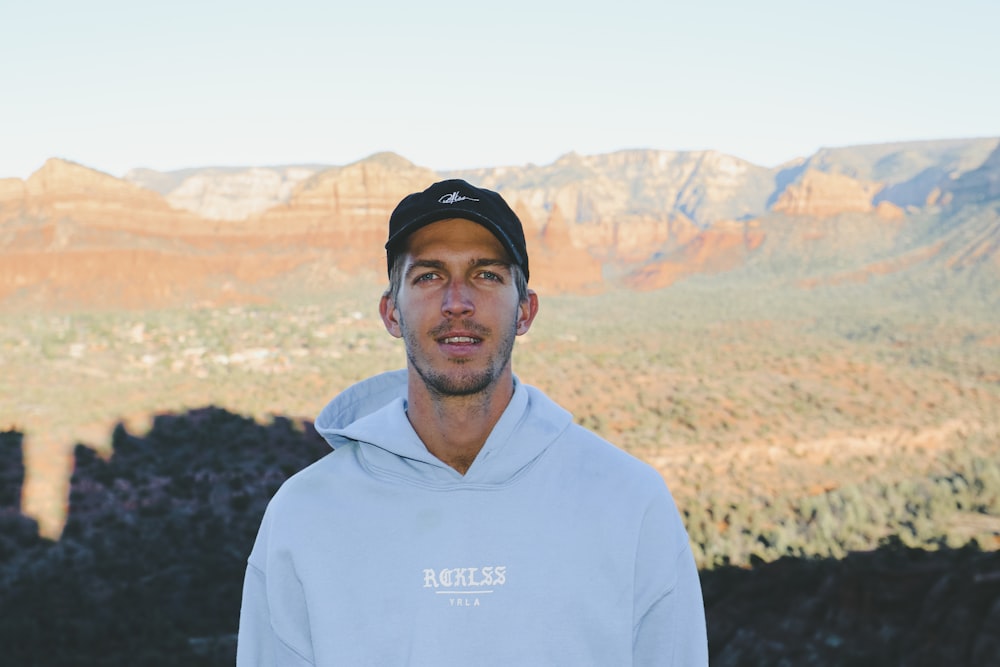 man in white hooded shirt by mountains during daytime