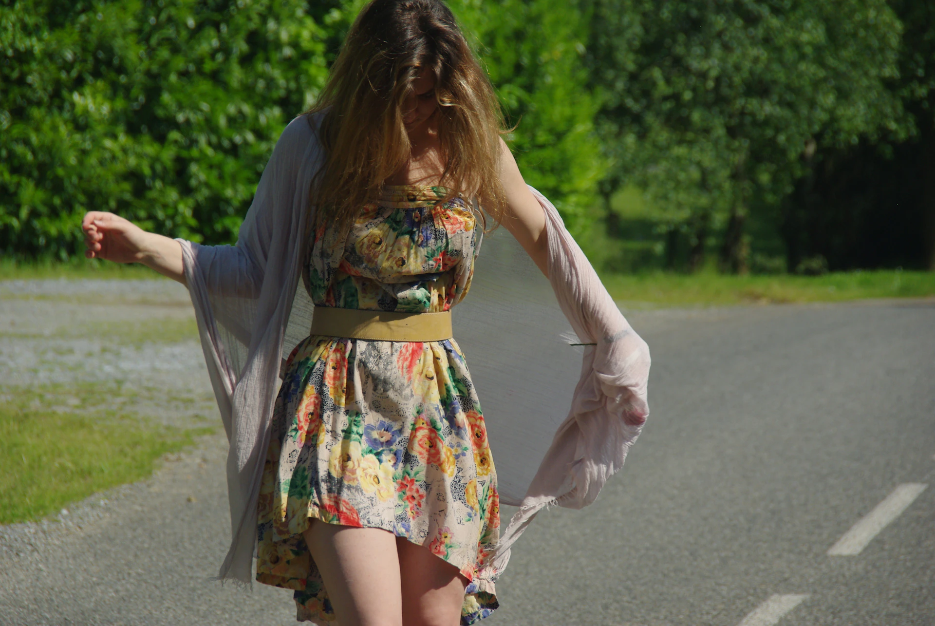 A joyful model wearing a flowing Asian dress, walking outdoors with sunlight filtering through trees, capturing the fabric's movement and vivid hues.