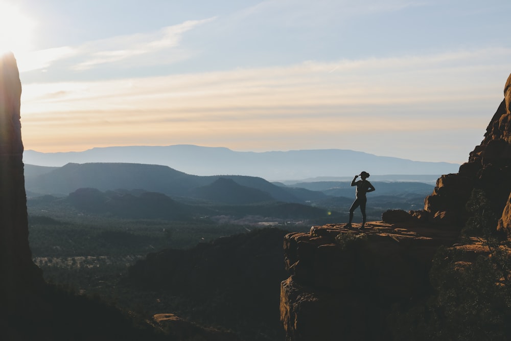 woman standing on cliff during sunset