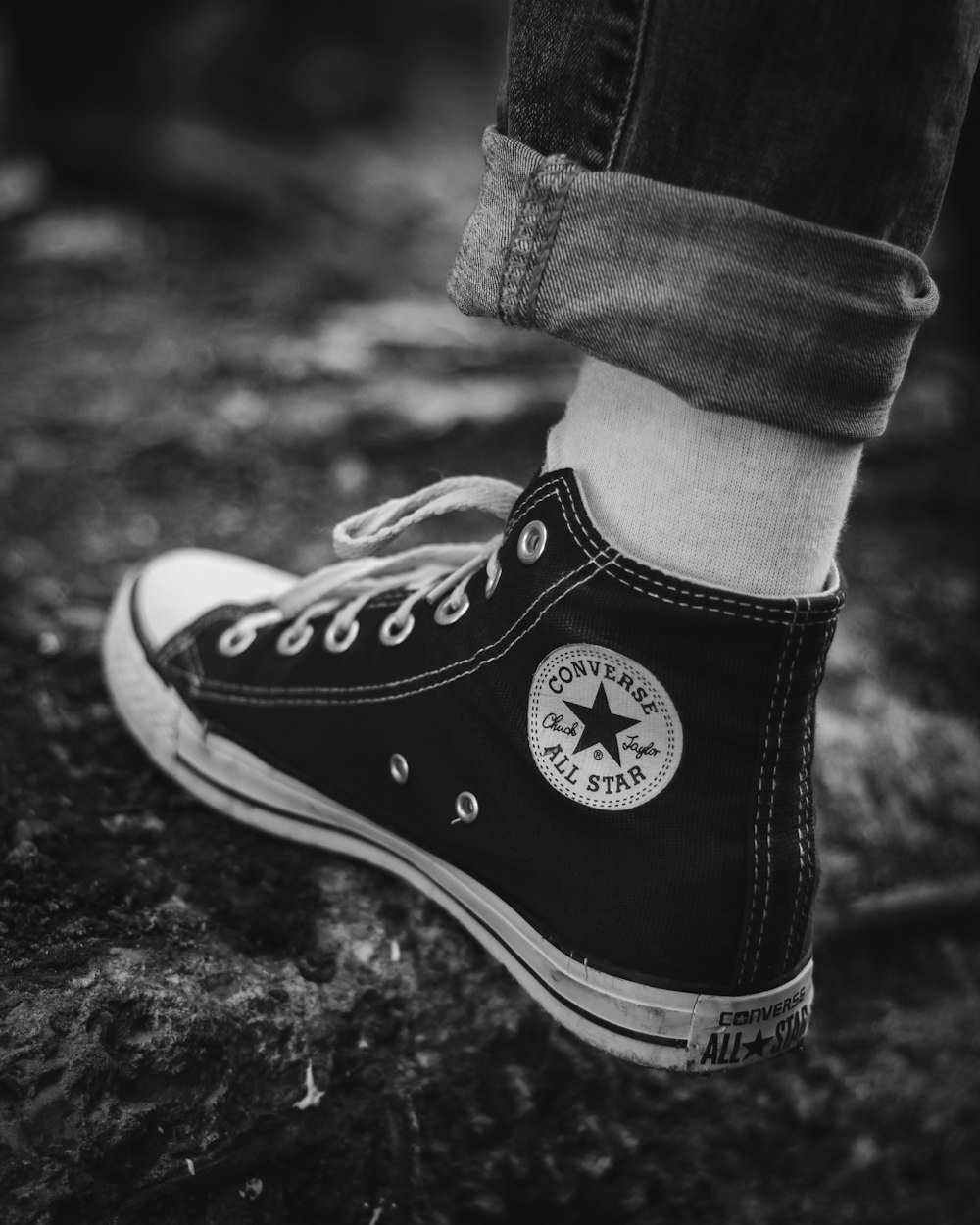 grayscale photography of person in Converse high-tops