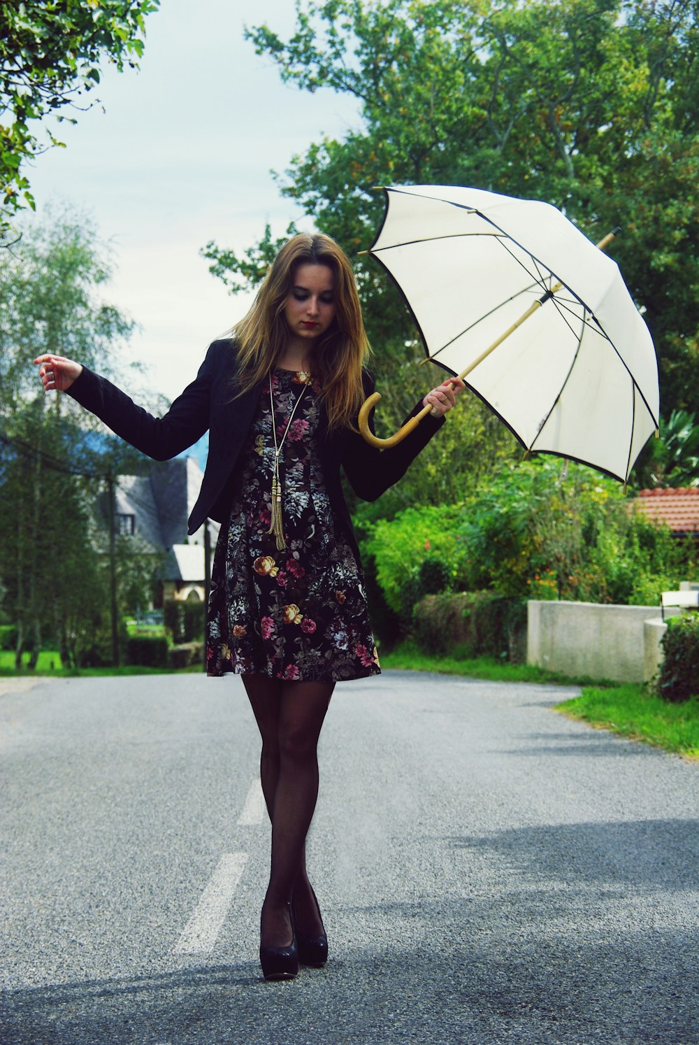 woman walking and holding umbrella during day