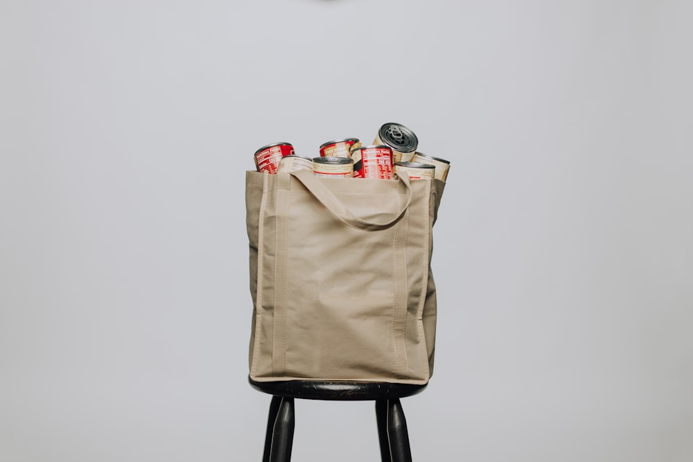 red labeled cans on white fabric handbag