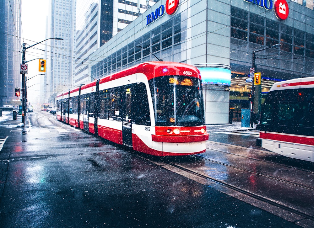 white and red bus on road near buildings during daytime