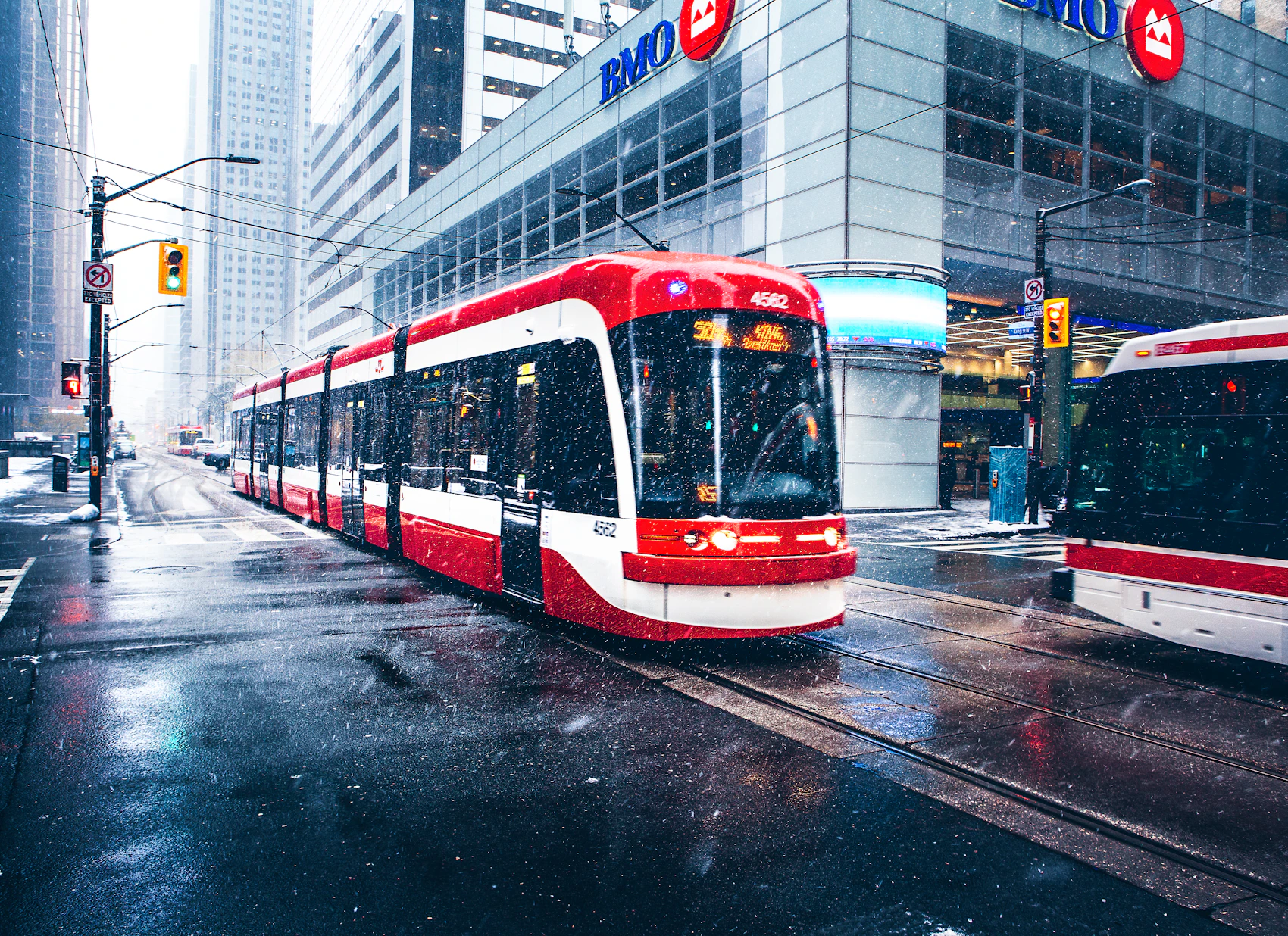 A red and white Toronto streetcar travelling through downtown on a snowy winter day