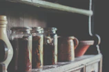 A rustic wooden shelf displaying vintage pottery and dried flower arrangements in warm sunlight