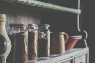 A rustic kitchen shelf displaying organized jars and vintage cookware.