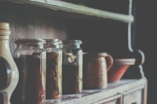 A rustic kitchen shelf displaying organized jars and vintage cookware.