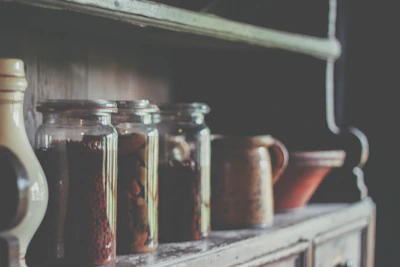Sunlit wooden kitchen counter displaying jars of preserves and vintage cooking utensils