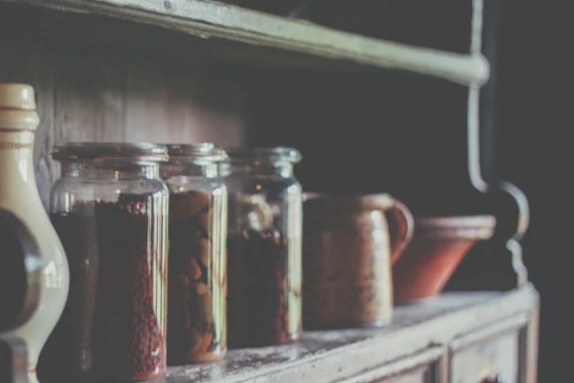 Ceramic canister set on a rustic kitchen shelf catching natural light.