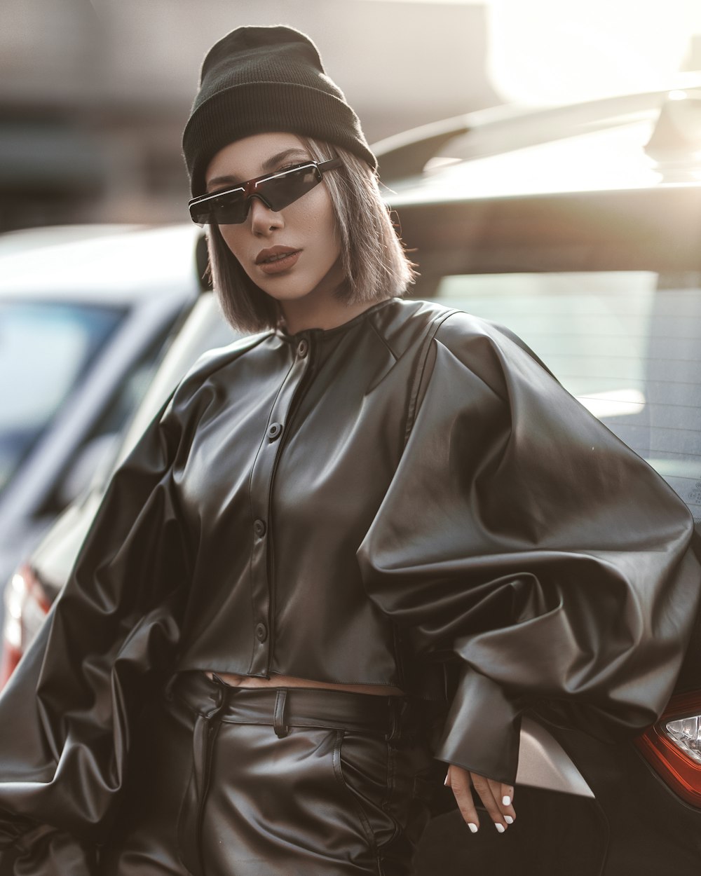 woman wearing black leather long-sleeved blouse standing and leaning on vehicle