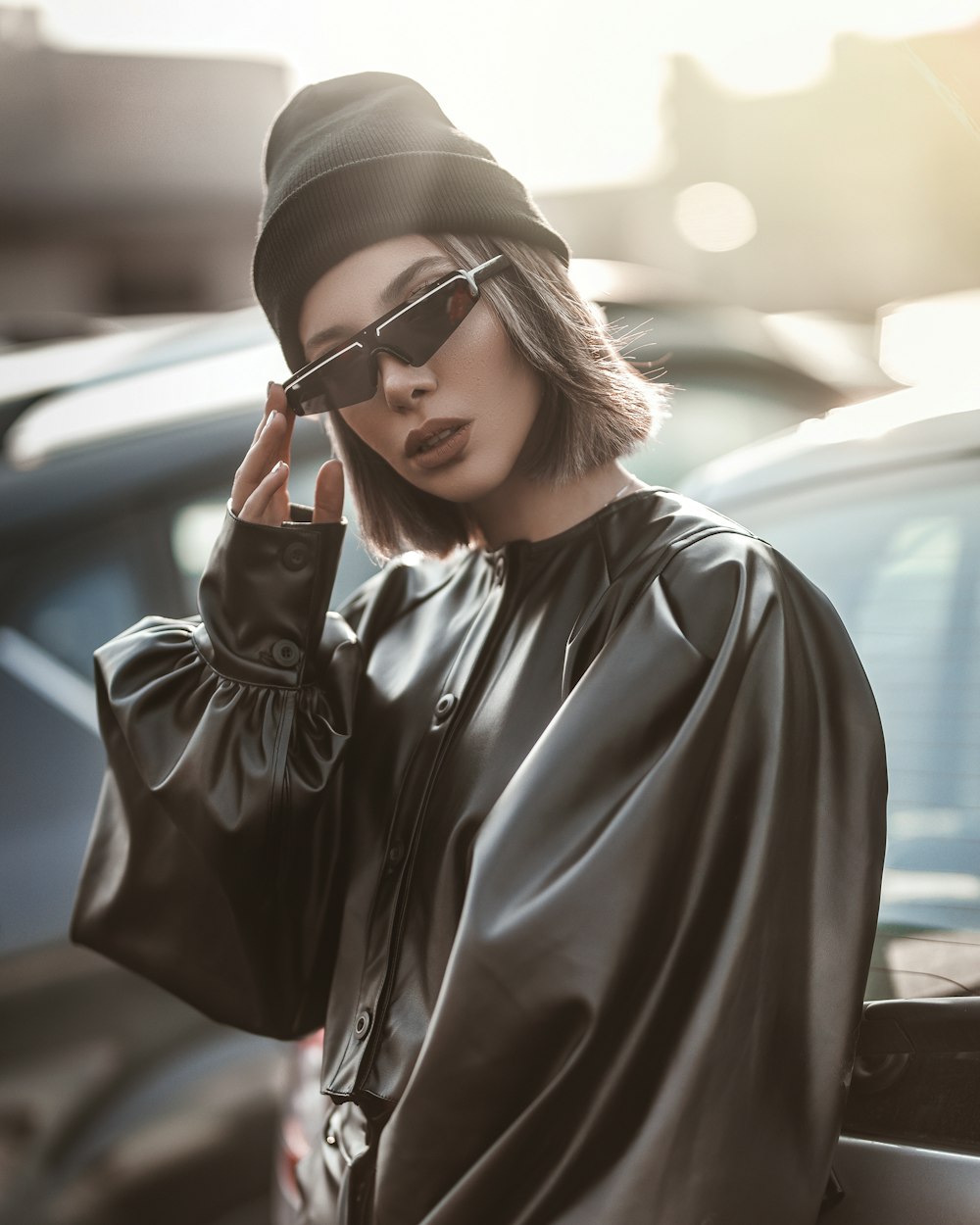 woman wearing black long-sleeved blouse and sunglasses standing near vehicle