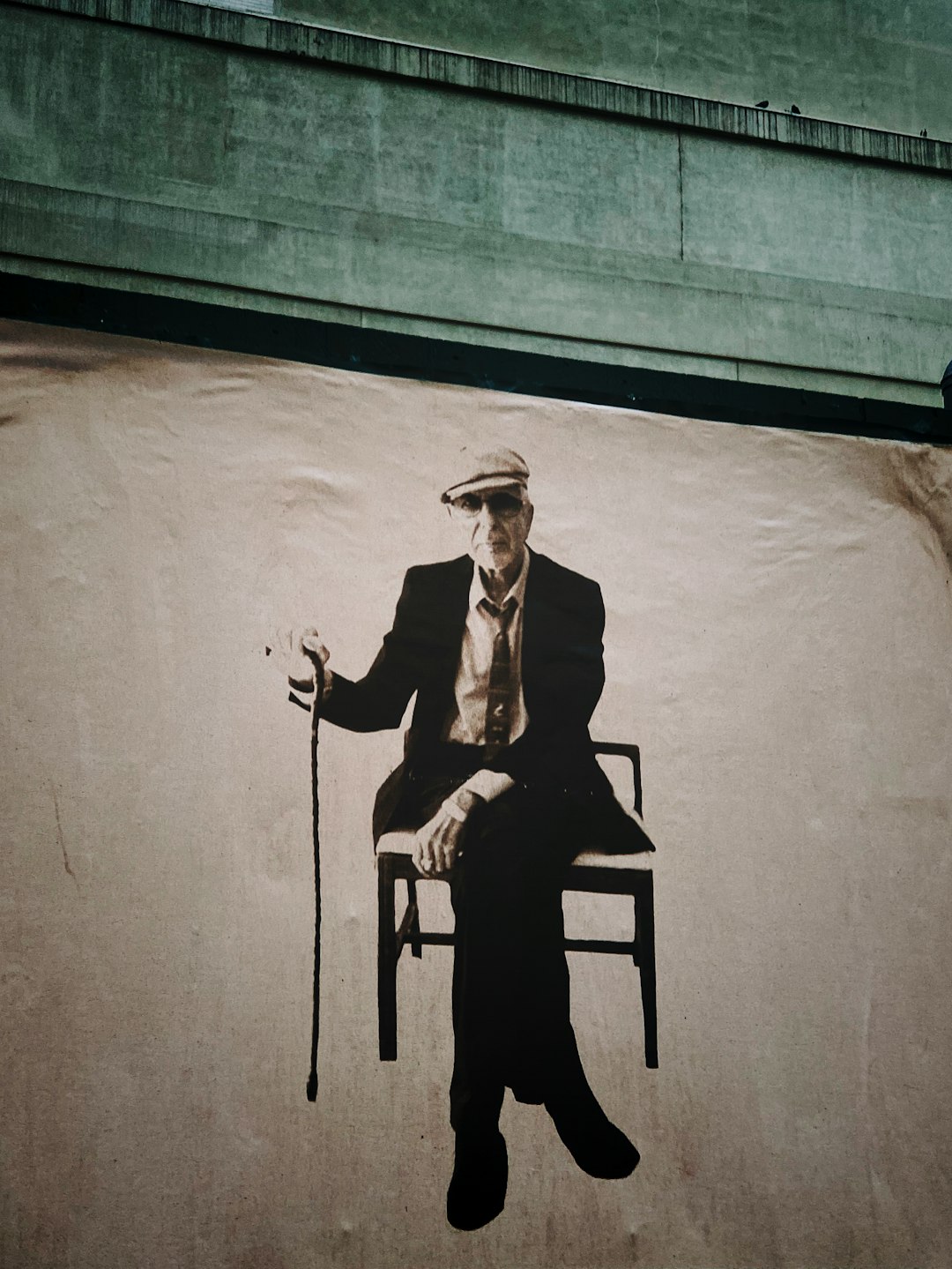 grayscale photography of man wearing suit holding walking cane sitting with crossed legs