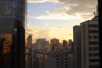 City skyline with various residential and commercial buildings at sunset.