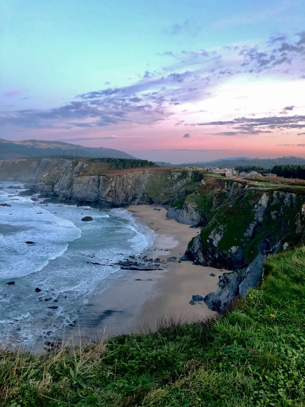 cliff viewing body of water under blue and white sky