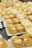 An assortment of small desserts is arranged on white plates. The foreground features tartlets with creamy fillings and crumbled toppings, while the background shows colorful layered cakes. The setting seems to be a buffet or dessert table.