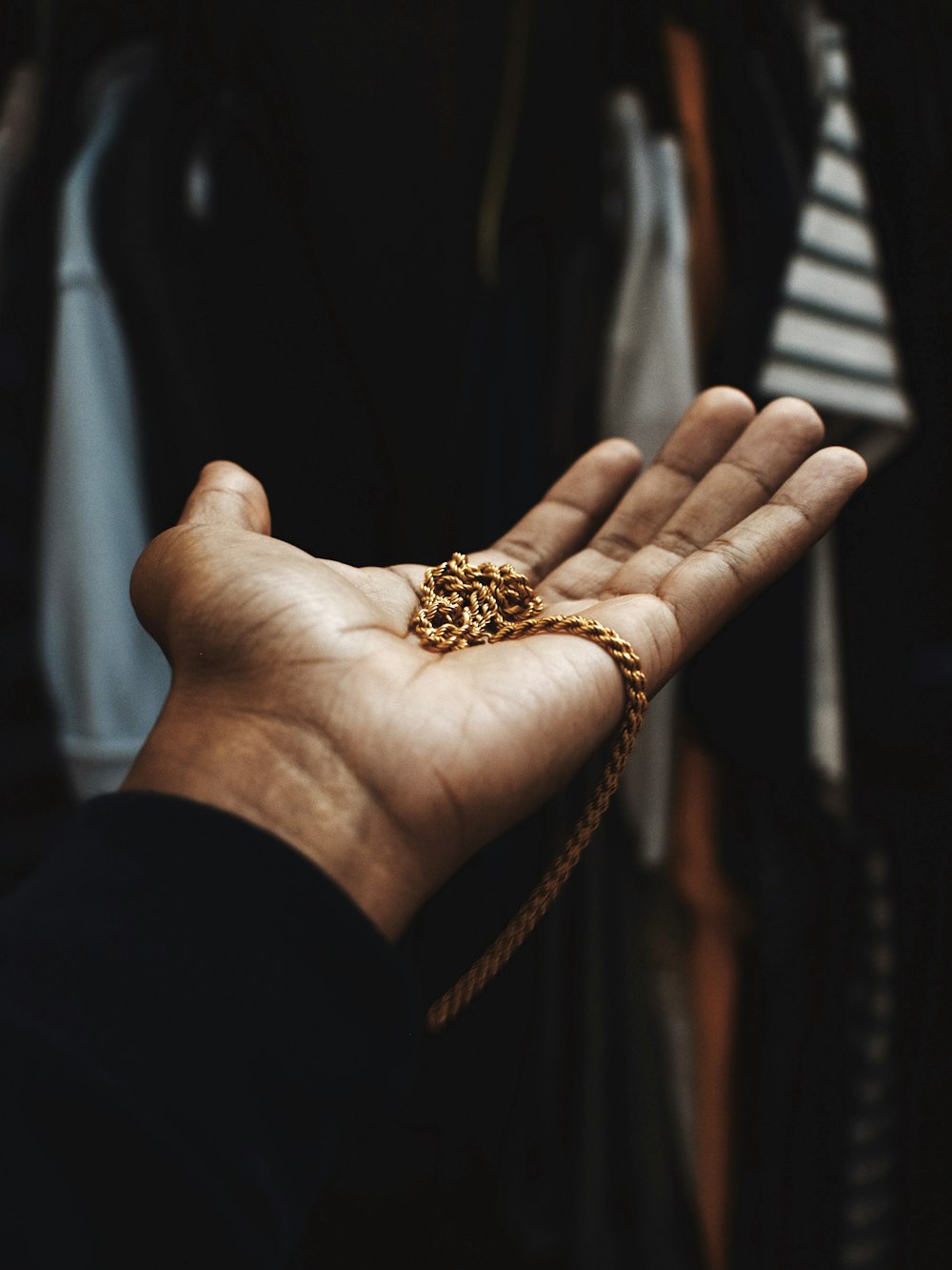 person holding chain gold-colored necklace