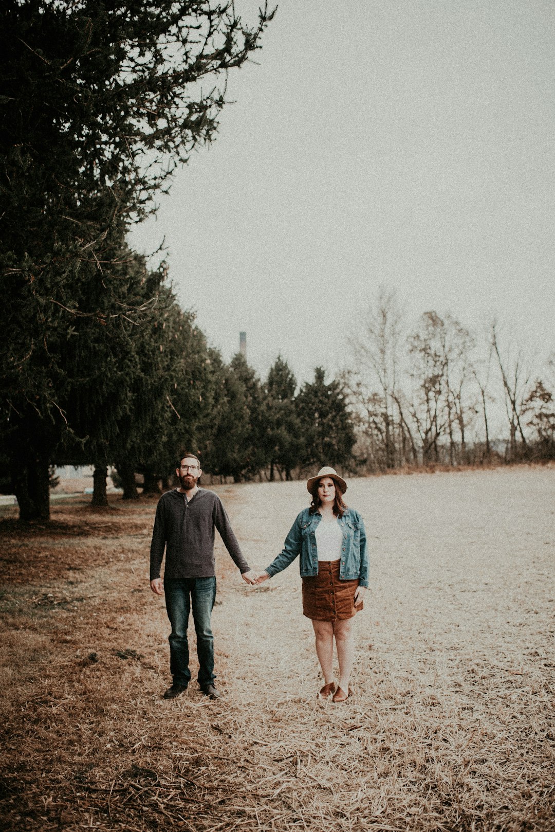 man and woman holding hands while standing on green field
