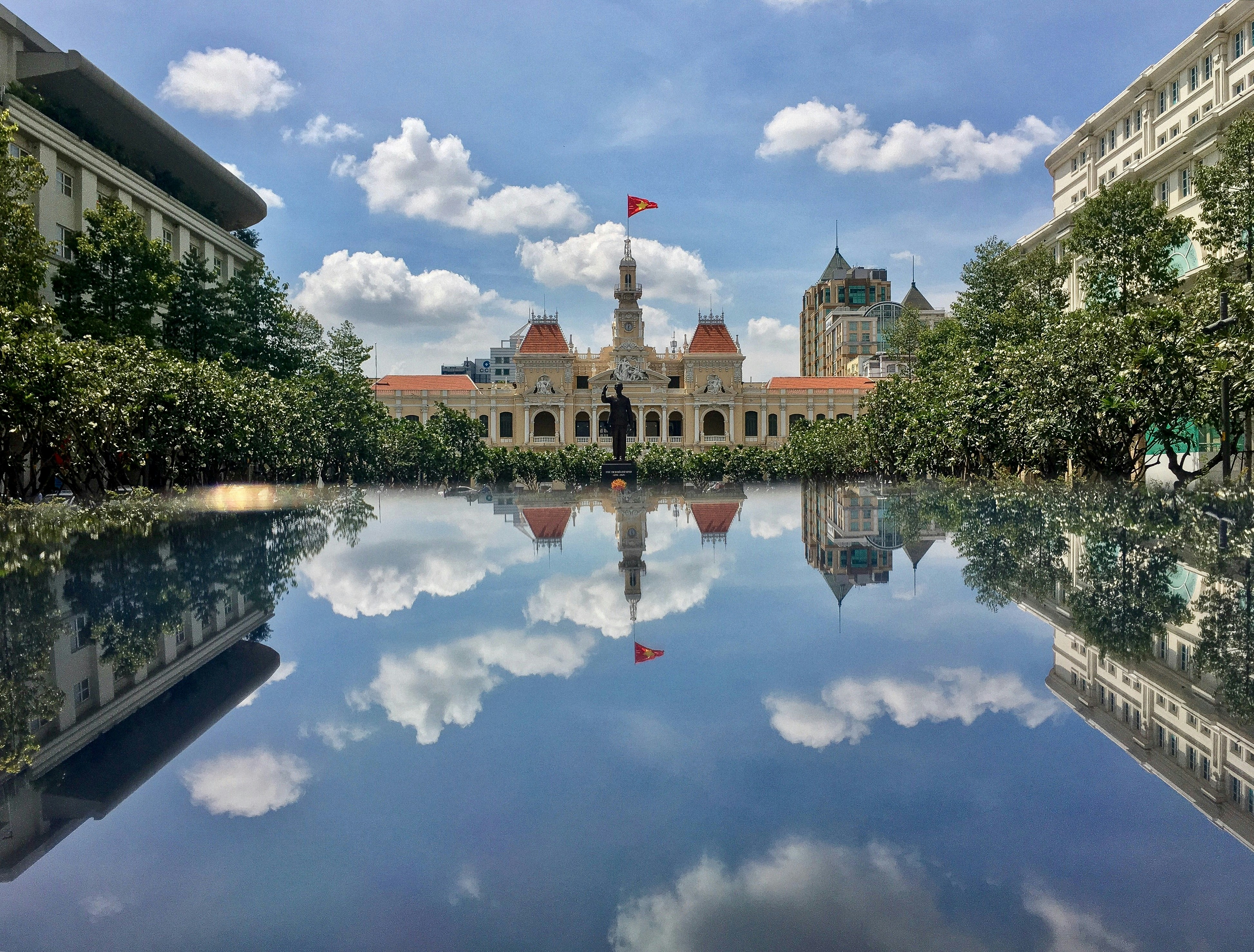 pond, trees, and buildings during day