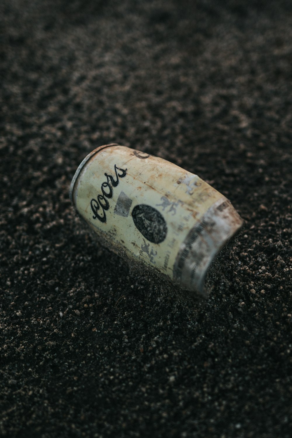 Coors beer can on black sand