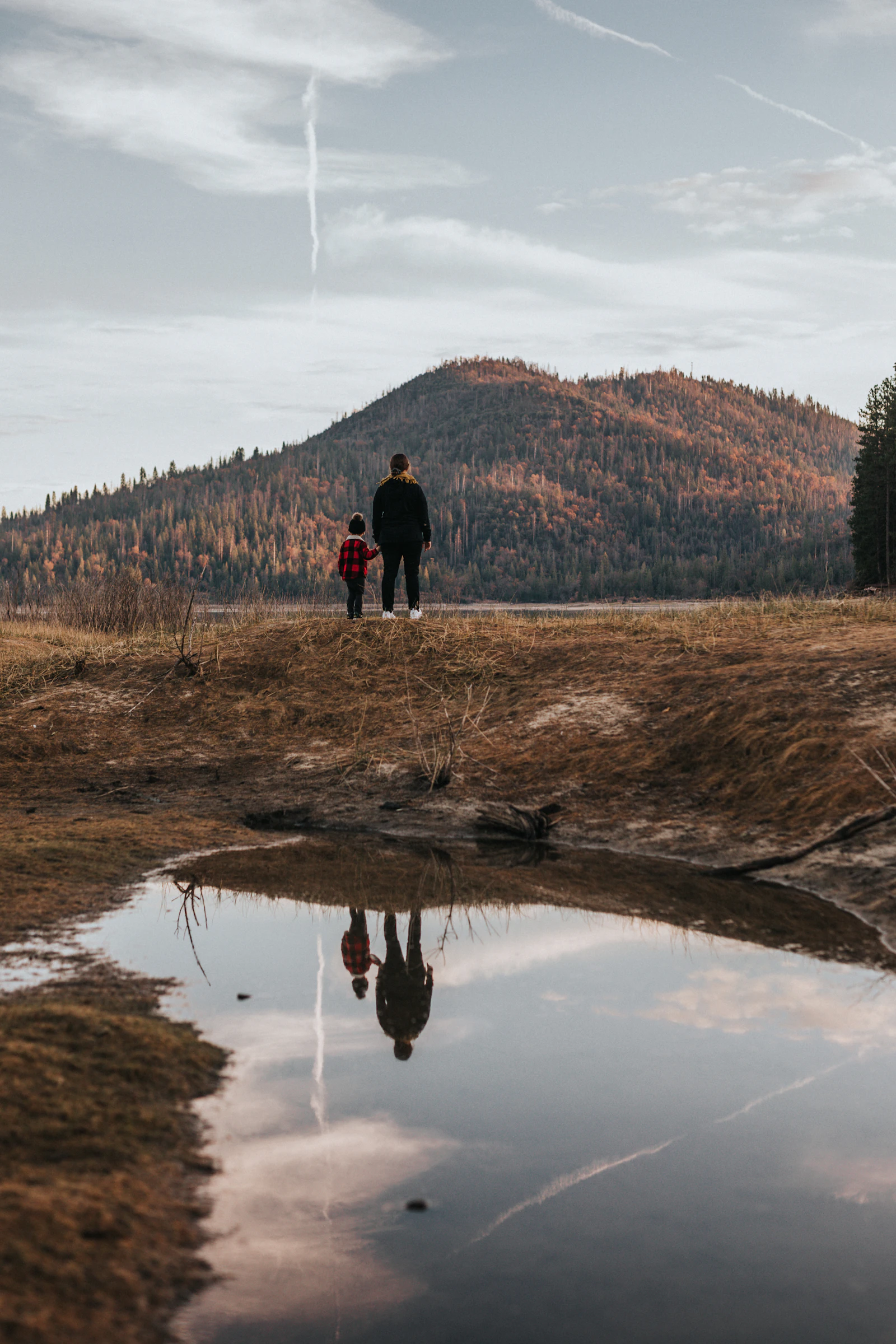 Un adulte et un enfant face à la montagne sur un sentier
