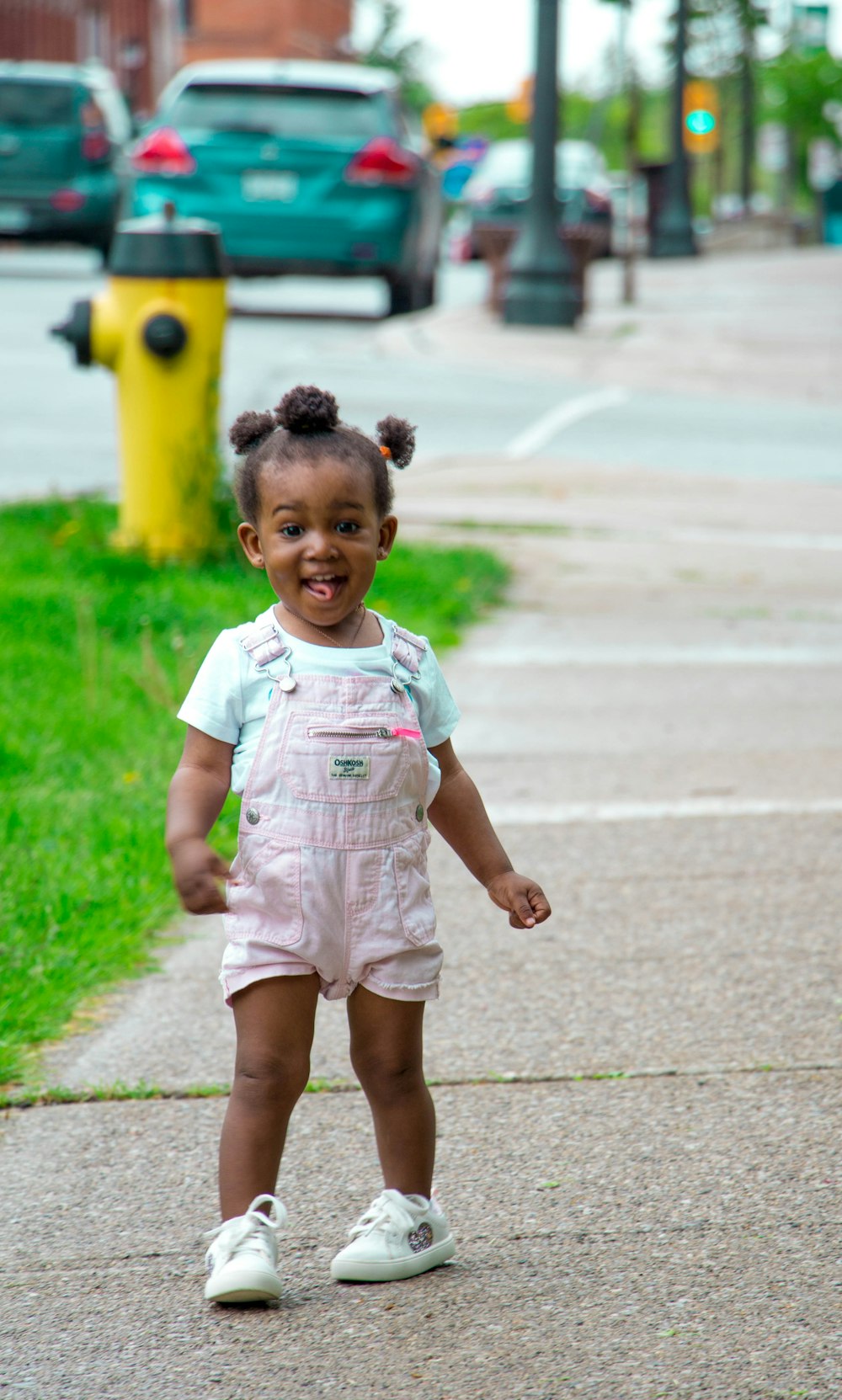 girl in pin k shortalls and white sneakers