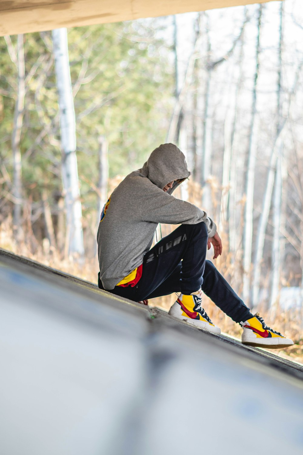 person in gray hoodie, black jeans, and yellow-white-and-ed Nike sneakers