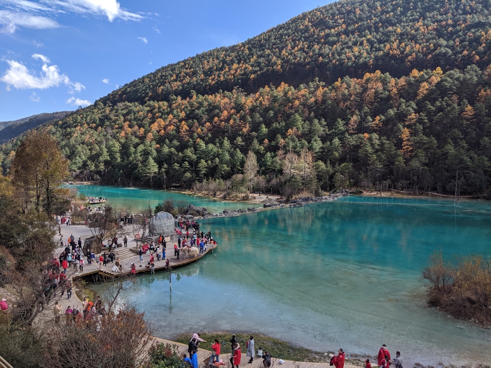 people by body of water and mountain slope at daytime