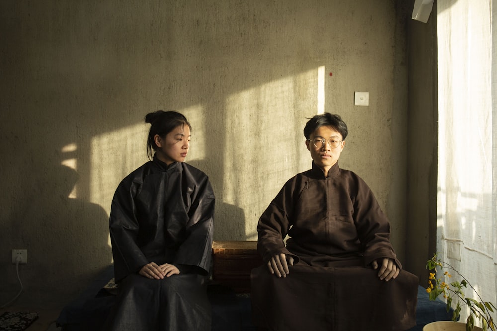 man and woman in robes by concrete wall at daytime