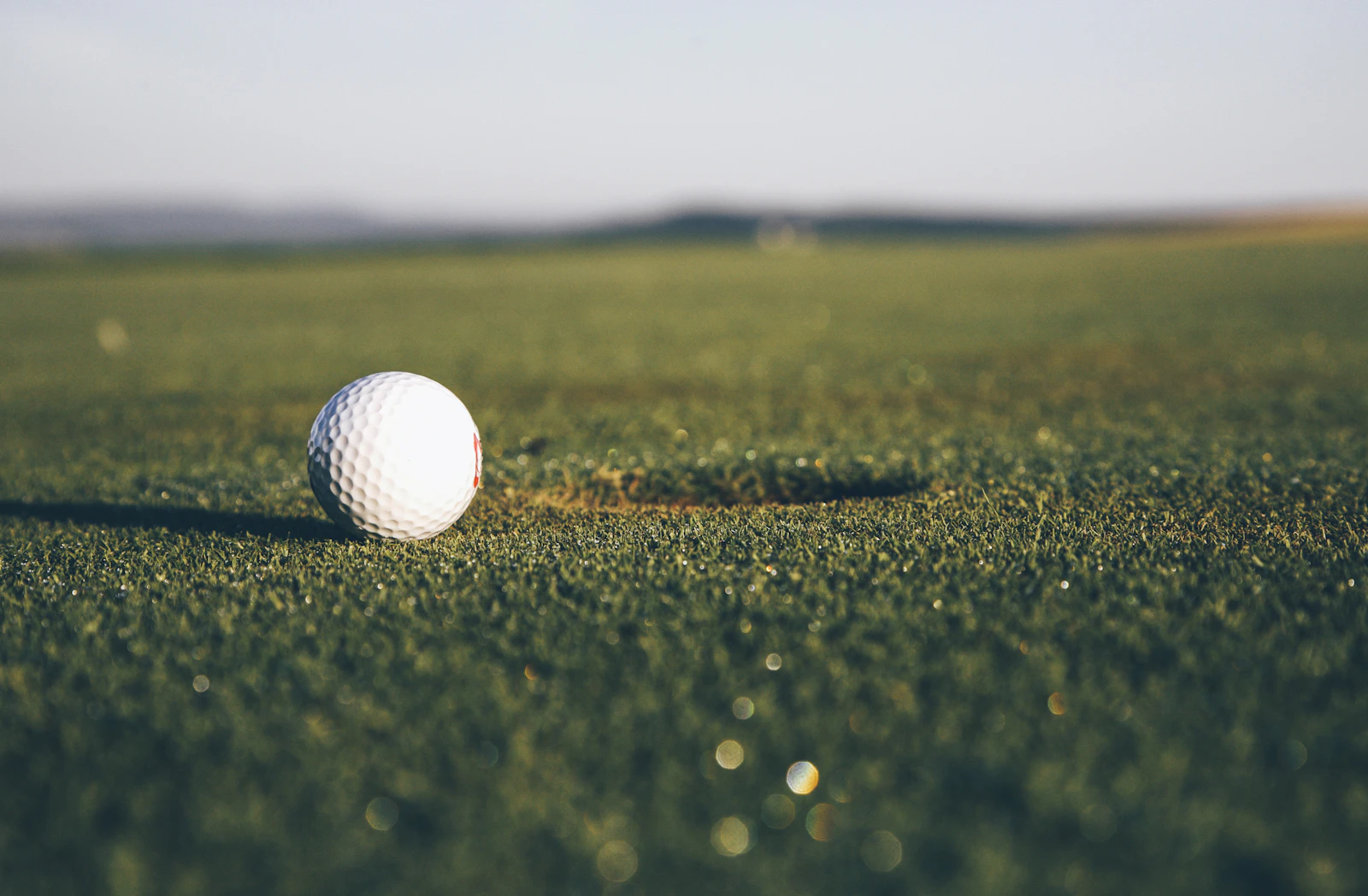 Golf ball resting on the turf at sunset