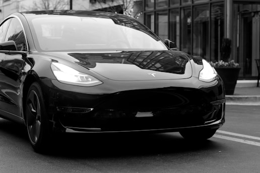 grayscale photography of Grand tourer parking near road