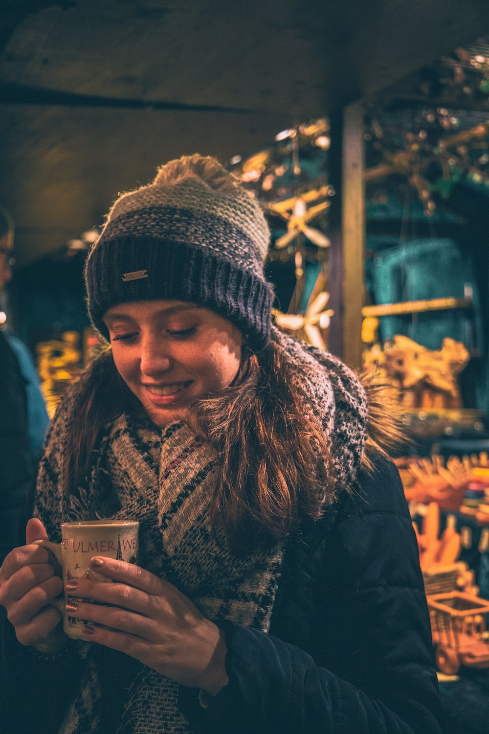 smiling woman holding mug by wooden post