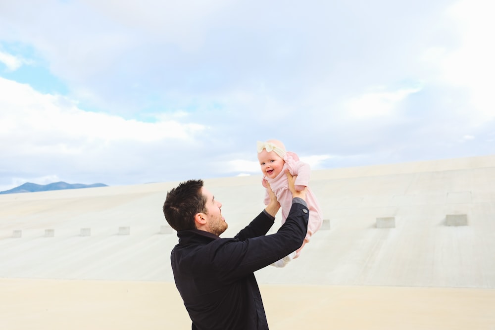 man carrying baby during daytime